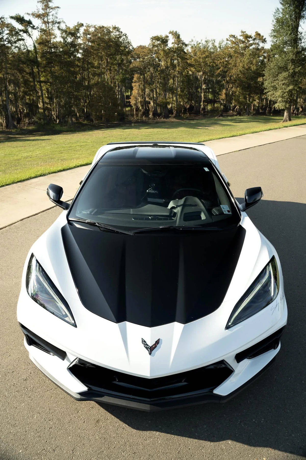 Front view of white Chevrolet Corvette C8 with black wrapped hood
