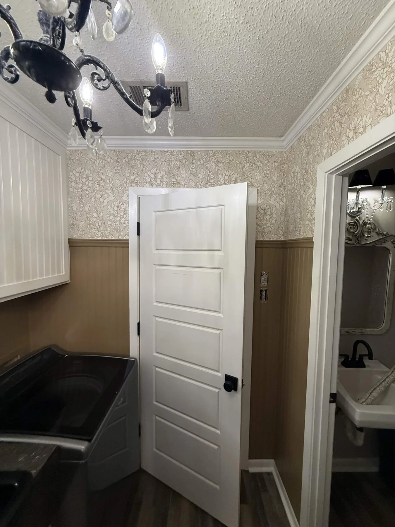 Floral wallpaper installed above wall paneling in a residential laundry room